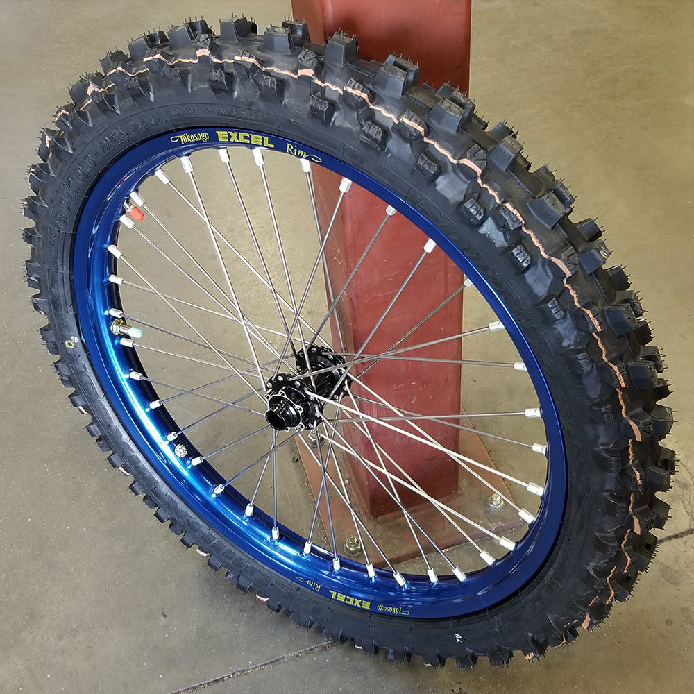 Woody's custom wheel with blue Excel rim and black hub, w/ a Knobby dirt tire mounted on the wheel