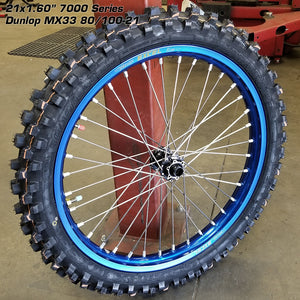 Woody's custom wheel for Sur Ron w/ a blue Excel rim and black hub, w/ knobby tire mounted