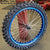 Woody's custom wheel for Sur Ron w/ a blue Excel rim and black hub, w/ knobby tire mounted