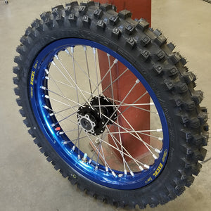 Woody's custom rear wheel for Sur Ron w/ blue Excel rim and black hub, and knobby tire mounted