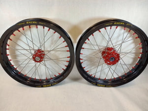 Woody's custom "super moto" wheelset for Sur Ron e-bikes. Black Excel rims w/ red billet hubs and red spoke-nipples.